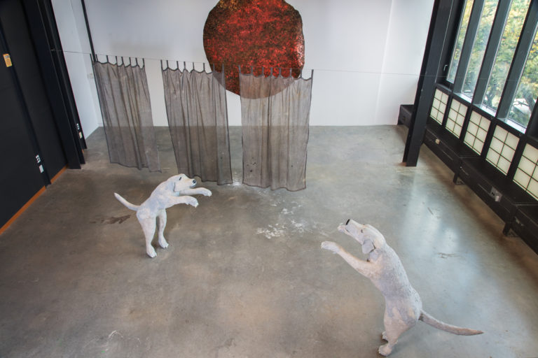Installation of artwork titled “dancing with London”: two sculptures of Emilie Gossiaux's guide dog London standing on hind legs and reaching out across the space to eachother with their front legs, as if to embrace in a slow dance.
